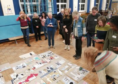 People standing around a collection of collage artwork laid out on the floor